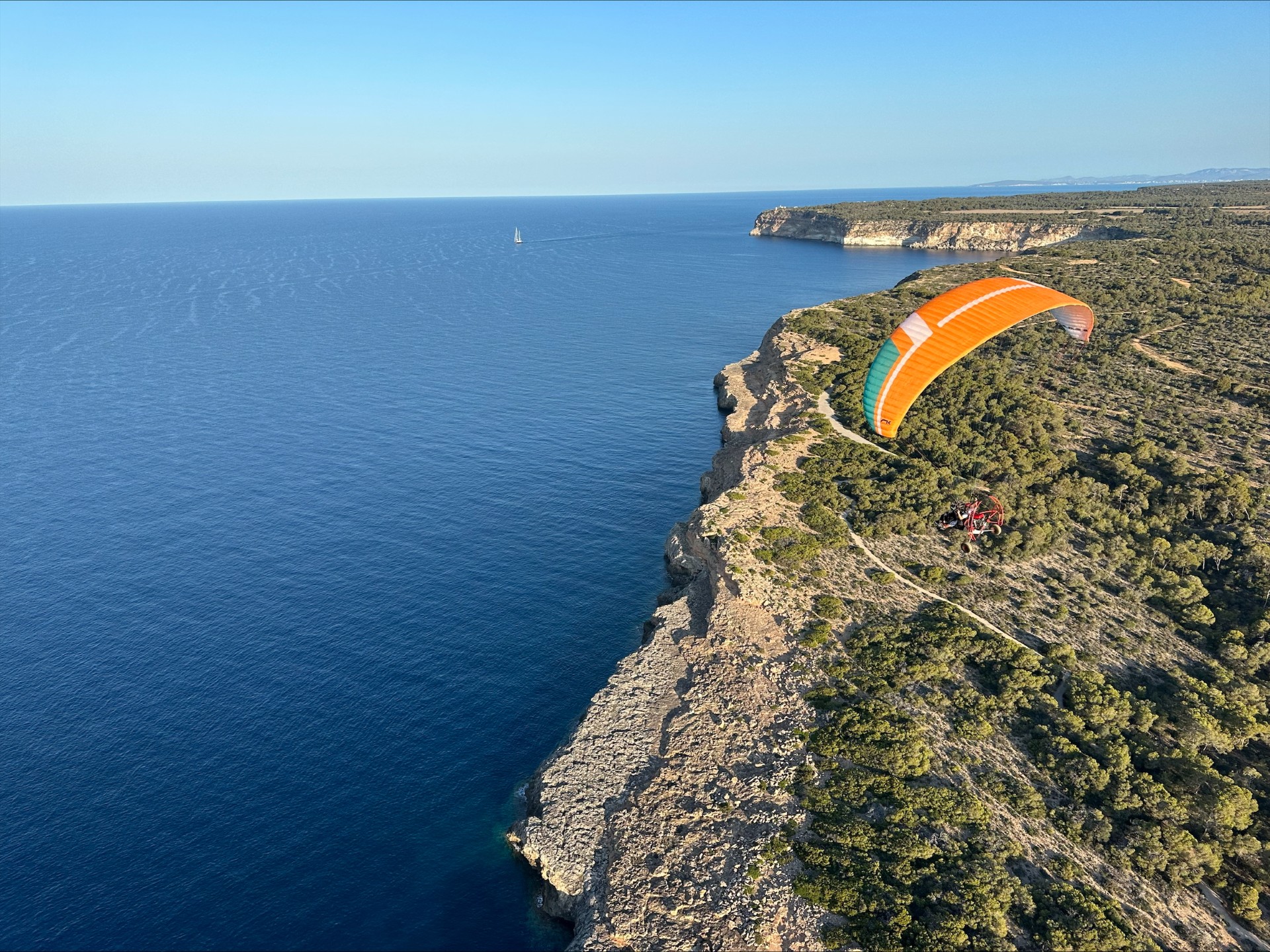 Paratrike de vela naranja sobre los acantilados de Mallorca