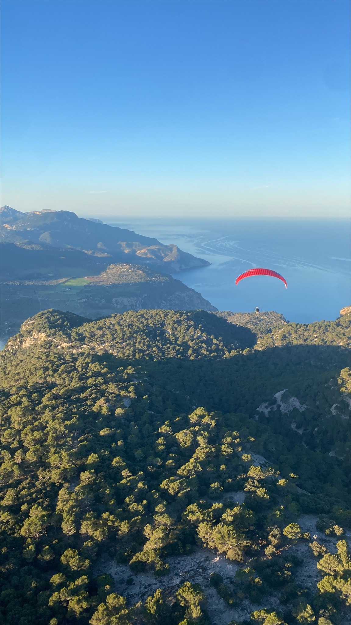 Parapente rojo entre el mar y las montañas de la Tramuntana